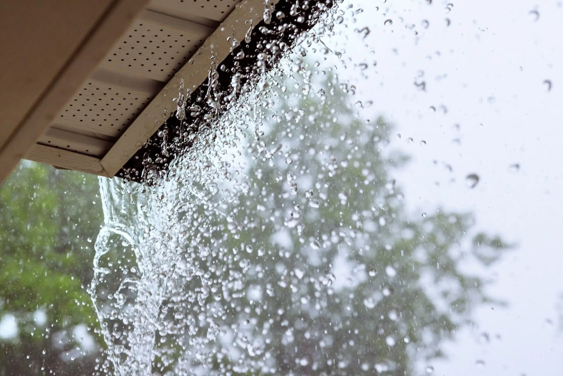Heavy rainstorm water pours over roof gutters